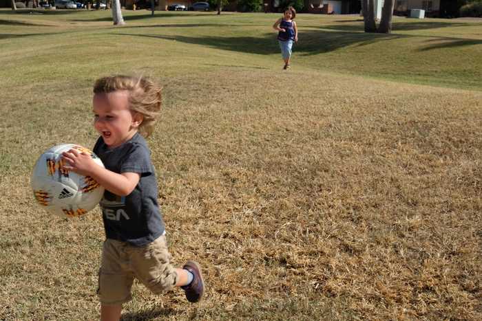 One kid is running out of frame of the picture as the other kid continues to run towards them