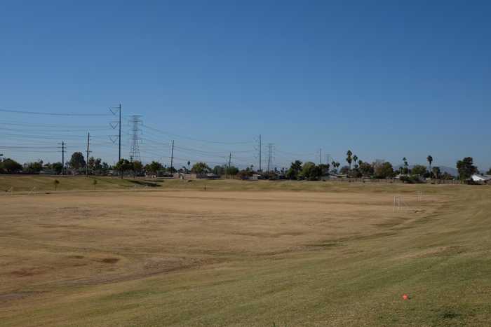 A big basin in a park with the canal and some powerlines behind it